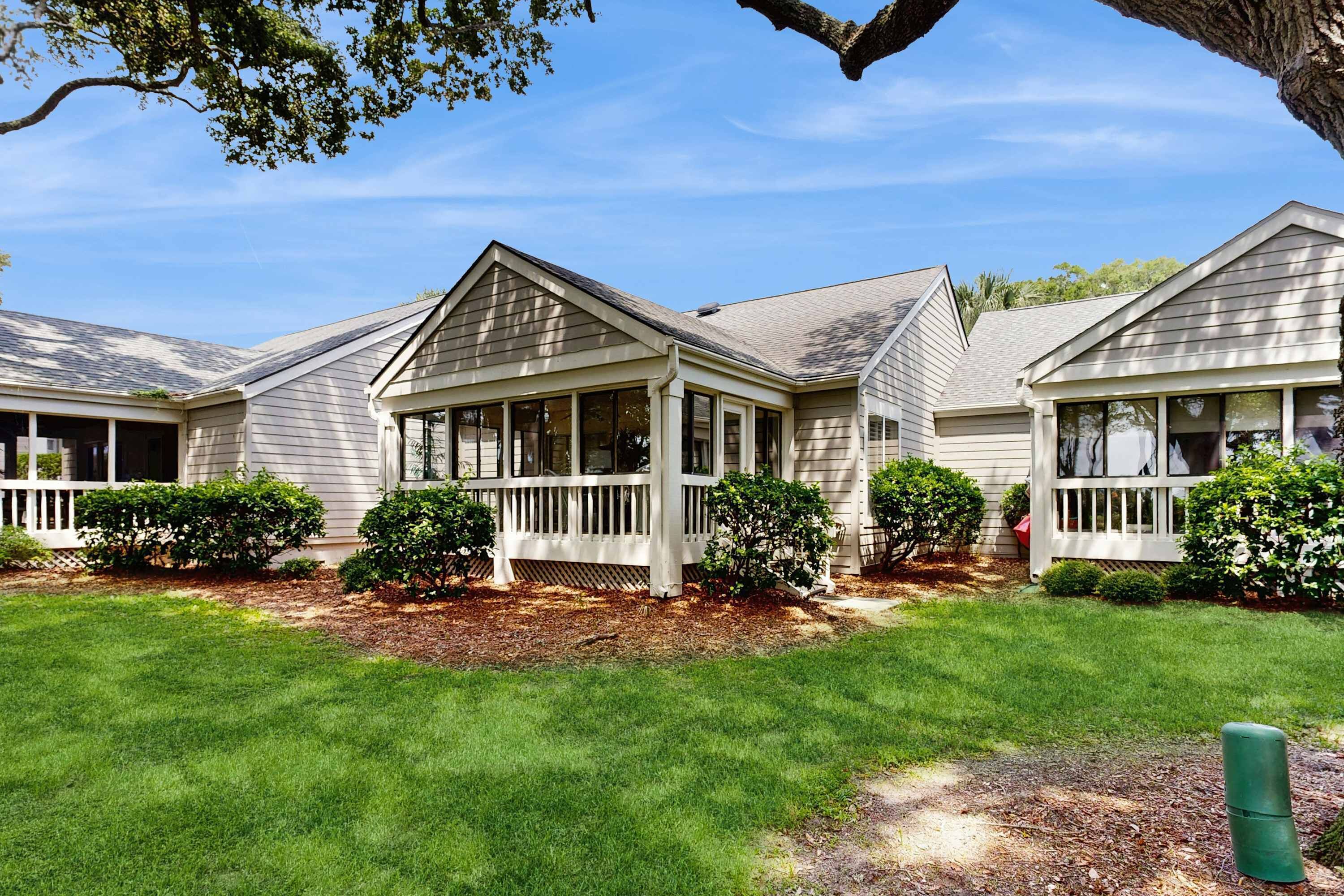 A row of two-story houses with a covered porch and a well-maintained lawn.