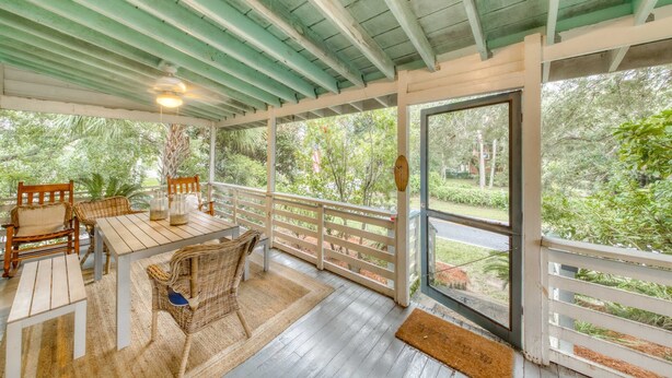 Une terrasse couverte avec une table et des chaises, un plafond en bois et une vue sur la verdure environnante.