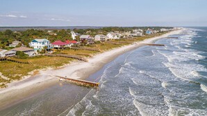 Une zone résidentielle côtière avec des maisons le long de la plage, une jetée en bois et une rive sablonneuse.