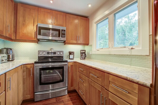 A modern kitchen with wooden cabinets, stainless steel appliances, and a window providing natural light.