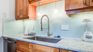 A kitchen with wooden cabinets, a stainless steel sink, and a built-in blender. - Palm-surrounded abode with screened-in balcony, chef's kitchen, smart TVs, & W/D (Isle of Palms)