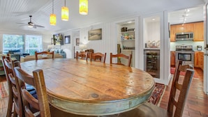 A spacious dining area with a large wooden table surrounded by chairs, a ceiling fan, and pendant lights. - Palm-surrounded abode with screened-in balcony, chef's kitchen, smart TVs, & W/D (Isle of Palms)