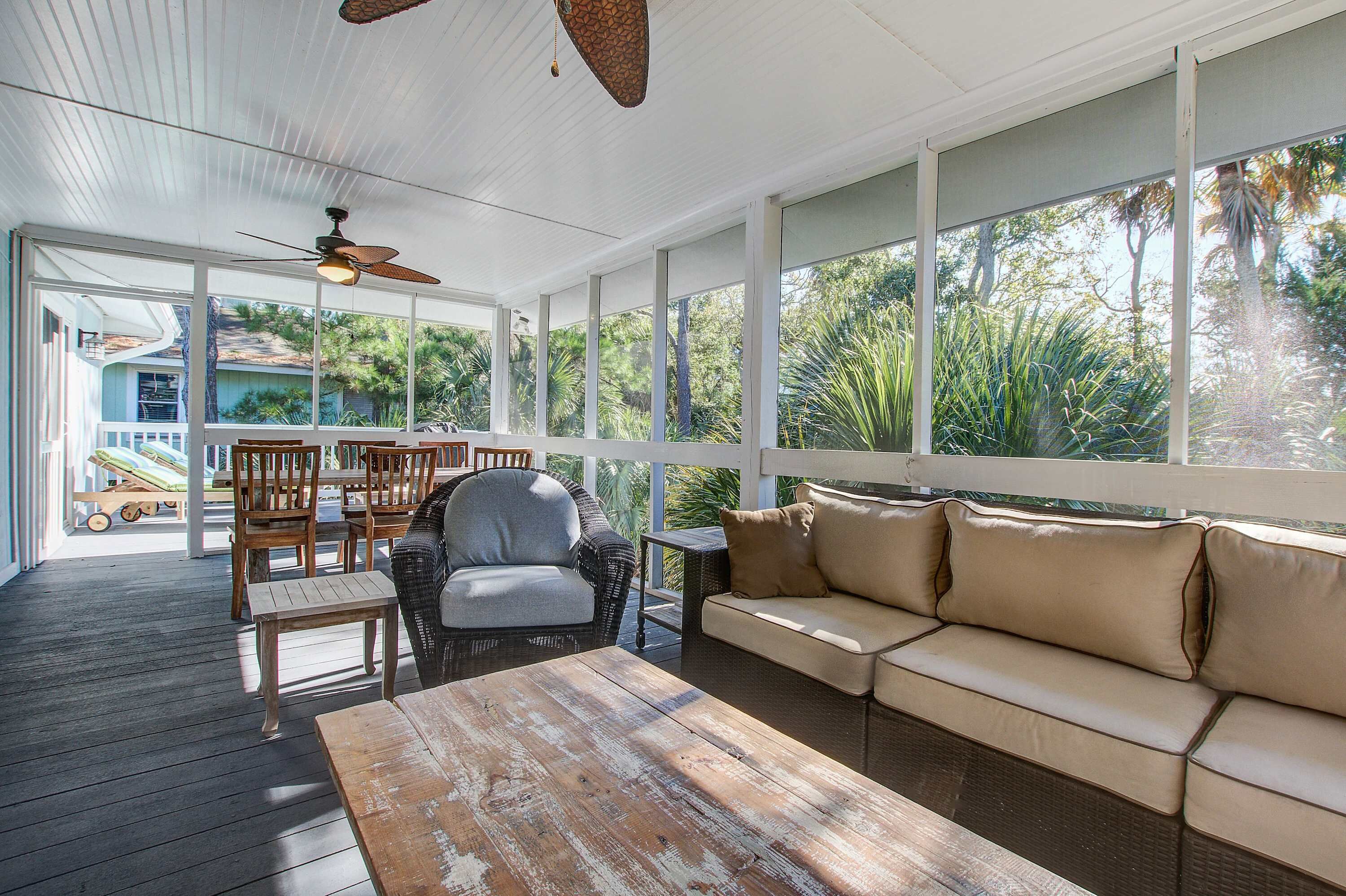 A covered outdoor area with a wooden table, a sofa, and chairs.