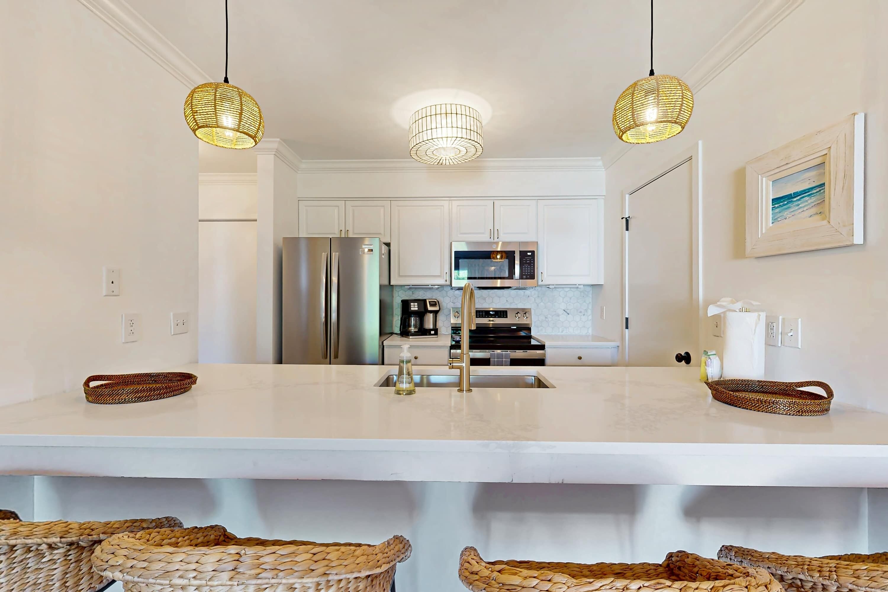 A modern kitchen with white cabinets, stainless steel appliances, and a central island with baskets.