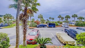 A parking lot with several cars and a trailer, surrounded by palm trees and greenery. - Updated Oceanfront Condo w/ Balcony, Pool & Beach Access (Isle of Palms)