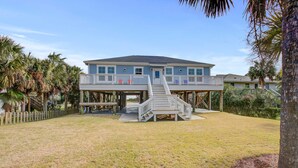 A two-story house with a covered deck and a staircase leading to the upper level. - Beautiful ocean view home w/ free WiFi is just across the street from the beach (Folly Beach)