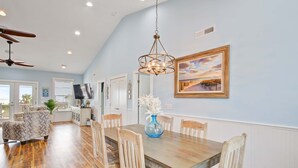 A dining area with a wooden table and chairs, a chandelier, and a painting on the wall. - Beautiful ocean view home w/ free WiFi is just across the street from the beach (Folly Beach)