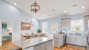 A modern kitchen with granite countertops, gray cabinets, and a central island. - Beautiful ocean view home w/ free WiFi is just across the street from the beach (Folly Beach)