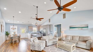 A spacious living room with hardwood floors, a dining area, and a kitchen. There are ceiling fans, recessed lighting, and a large window. - Beautiful ocean view home w/ free WiFi is just across the street from the beach (Folly Beach)