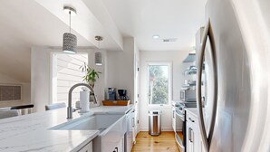 Uma cozinha moderna com bancada de mármore, eletrodomésticos de aço inoxidável e piso de madeira.