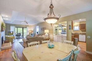 A spacious living area with a dining table, a sofa, and a kitchen in the background.
