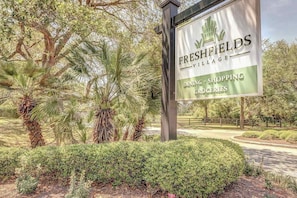Schild für Freshfields Village, das Gastronomie, Einkaufsmöglichkeiten und Lebensmittel bewirbt.