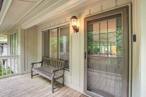 A porch with a bench, a door with a glass panel, and a wall-mounted light fixture.