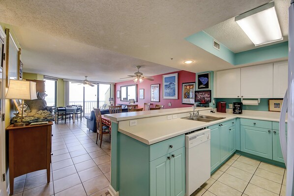 A kitchen with teal cabinets, a white countertop, and a ceiling fan. - Oceanfront, fourth-floor villa with balcony, amazing view & 2 shared pools (Folly Beach)