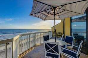 A balcony with a view of the beach, a table, and chairs. - Oceanfront, fourth-floor villa with balcony, amazing view & 2 shared pools (Folly Beach)
