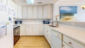 Une cuisine moderne avec des meubles blancs, un four à micro-ondes, une machine à café et un évier.