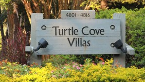 Ein Holzschild für Turtle Cove Villas mit der Zimmernummernfolge 4801-4816.