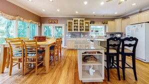A kitchen with wooden cabinets, a dining table with chairs, and a ceiling fan.