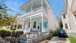 A two-story white house with a balcony, a small porch, and a black car parked in the driveway. - Historic upstairs condo in downtown Charleston w/free WiFi - perfect for groups (Charleston)