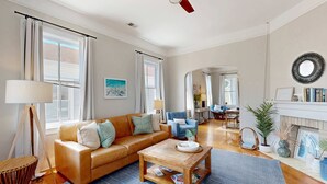 A spacious living room with a leather sofa, a wooden coffee table, and a blue rug. - Historic upstairs condo in downtown Charleston w/free WiFi - perfect for groups (Charleston)