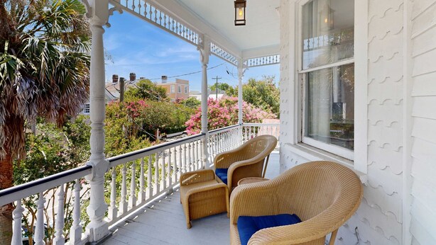 A covered porch with wicker furniture and a hanging lantern. - Historic upstairs condo in downtown Charleston w/free WiFi - perfect for groups (Charleston)