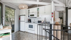 A modern kitchen with white cabinets, a microwave, an oven, and a coffee maker. - Lakefront home with lagoon view, deck & AC - close to beach, golf, & pools (Seabrook Island)
