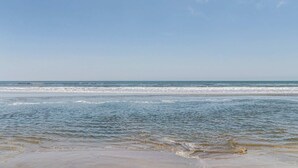Uma praia com céu claro e ondas calmas.