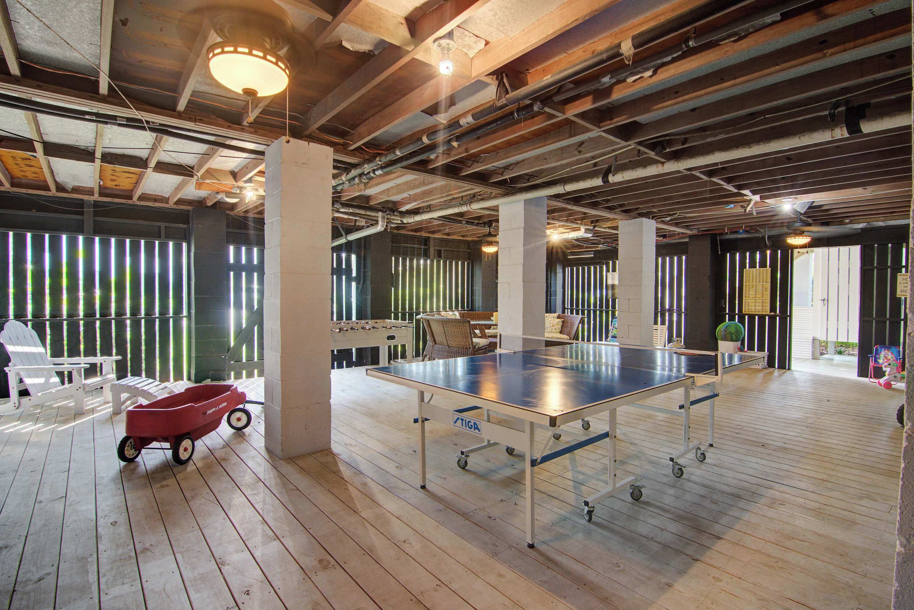 Un grand espace intérieur comprenant une table de ping-pong, un chariot rouge et une chaise blanche.