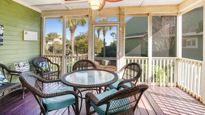 A covered porch with wicker furniture, a ceiling fan, and a view of palm trees and houses. - Townhouse-style villa with screened porch & pool access - short walk to beach (Isle of Palms)