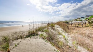 A beach with a wooden boardwalk leading to houses with green roofs. - Townhouse-style villa with screened porch & pool access - short walk to beach (Isle of Palms)