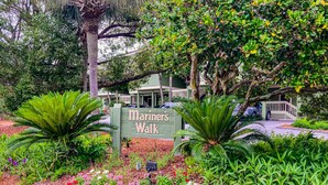 A sign for Mariner's Walk with a pathway, surrounded by lush greenery and flowering plants. - Townhouse-style villa with screened porch & pool access - short walk to beach (Isle of Palms)