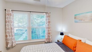 Un dormitorio con cama, cortinas, una ventana, un cuadro y una lámpara en el techo.