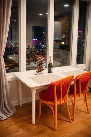 Comedor con una mesa y sillas, una botella de vino y una vinoteca con varias botellas.