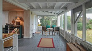 Une véranda avec un banc en bois, des meubles en osier et une table avec des chaises.
