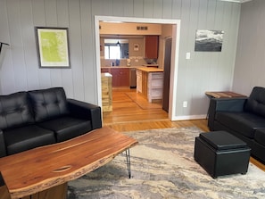 Un salon avec deux canapés noirs, une table basse en bois et un tapis.