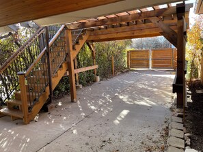 A covered wooden staircase leading to a gated driveway.