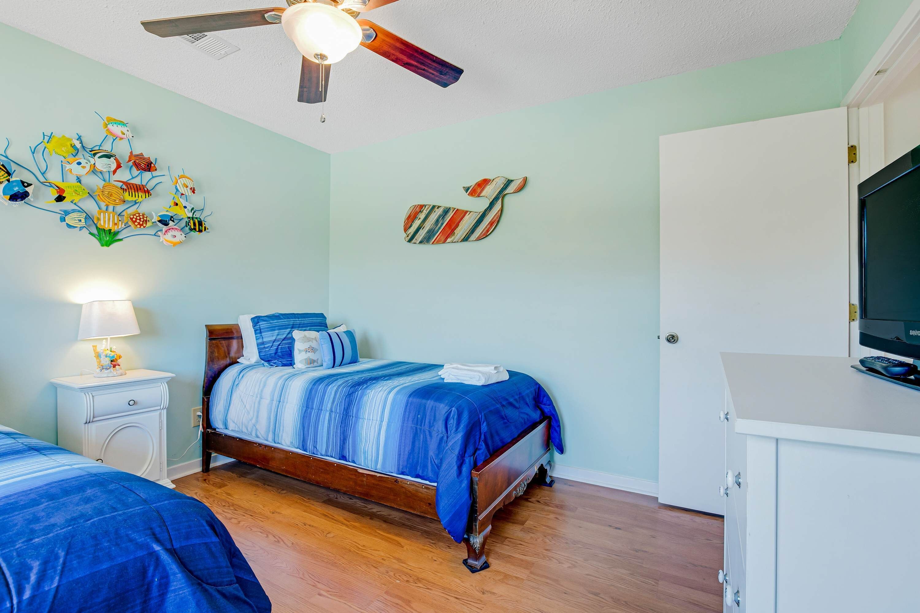 Une chambre à coucher avec un lit, une table de chevet et un ventilateur de plafond.