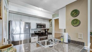 A modern kitchen with stainless steel appliances, granite countertops, and decorative wall plates. - Beach villa with full kitchen, ocean/inlet views - short walk to Beach Club (Seabrook Island)