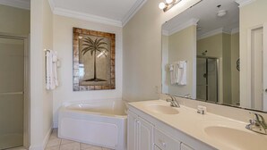 A bathroom with a large mirror, two sinks, a bathtub, and a shower.