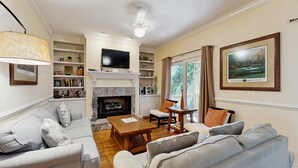A living room with a fireplace, a television, and a bookshelf. - Spacious home with pool - walk to beach & golf (Kiawah Island)