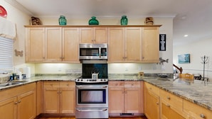 A kitchen with wooden cabinets, a stainless steel oven, a microwave, and a granite countertop. - Spacious home with pool - walk to beach & golf (Kiawah Island)