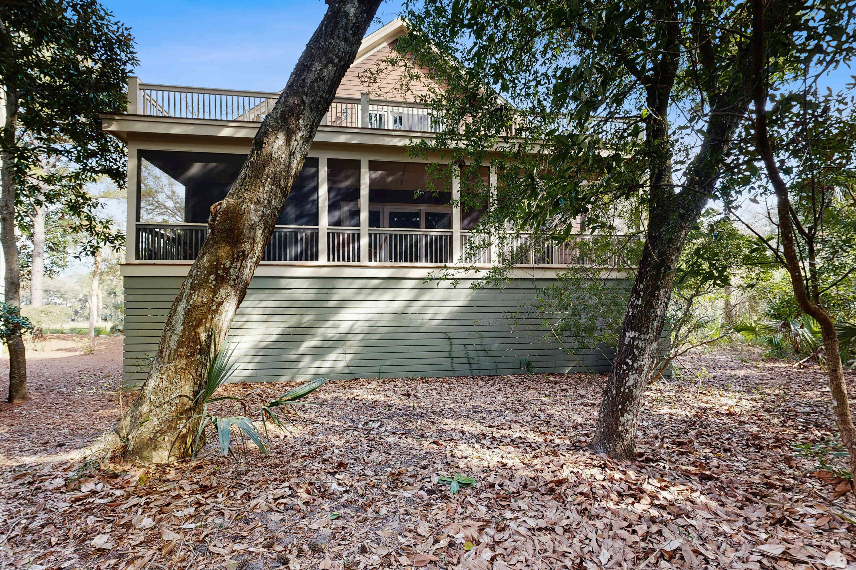 A two-story building with a balcony, surrounded by trees and a leaf-covered ground.