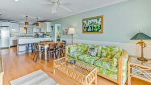 A living room with a sofa, coffee table, and dining area. - Oceanfront, event-friendly home with multiple decks & WiFi - 2 dogs ok (Folly Beach)