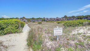 Un camino que conduce a una hilera de casas frente al mar, con un letrero que dice 'Private Property'.