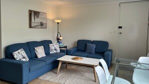 A modern living room with two blue sofas, a small white table, and a floor lamp.