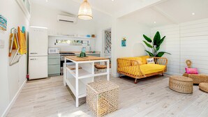 A modern kitchen with white appliances, a wooden dining table, and a yellow sofa. - Trio of coastal cottages with private courtyard, full kitchens, & WiFi - dogs ok (Folly Beach)