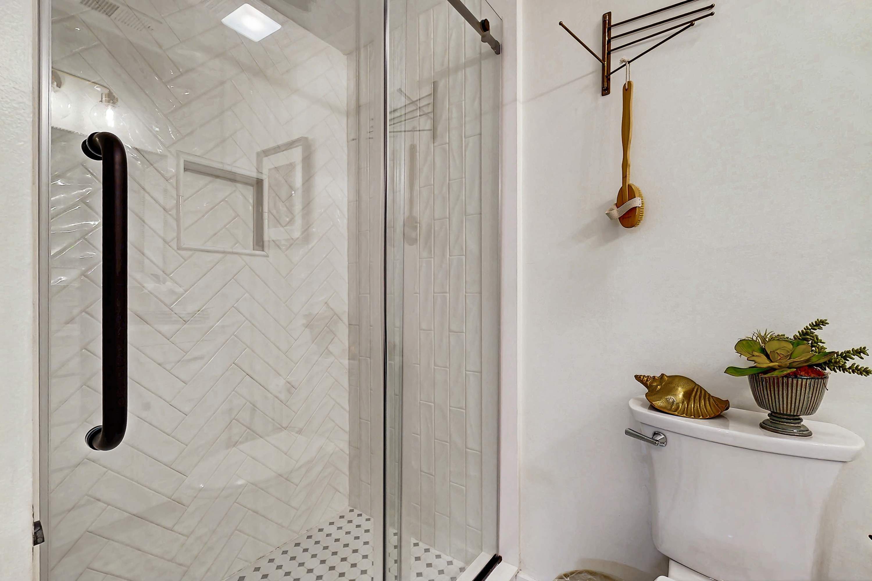 Een badkamer met een douche met glazen wand, een toilet met decoratieve accessoires en een handdoekhouder.