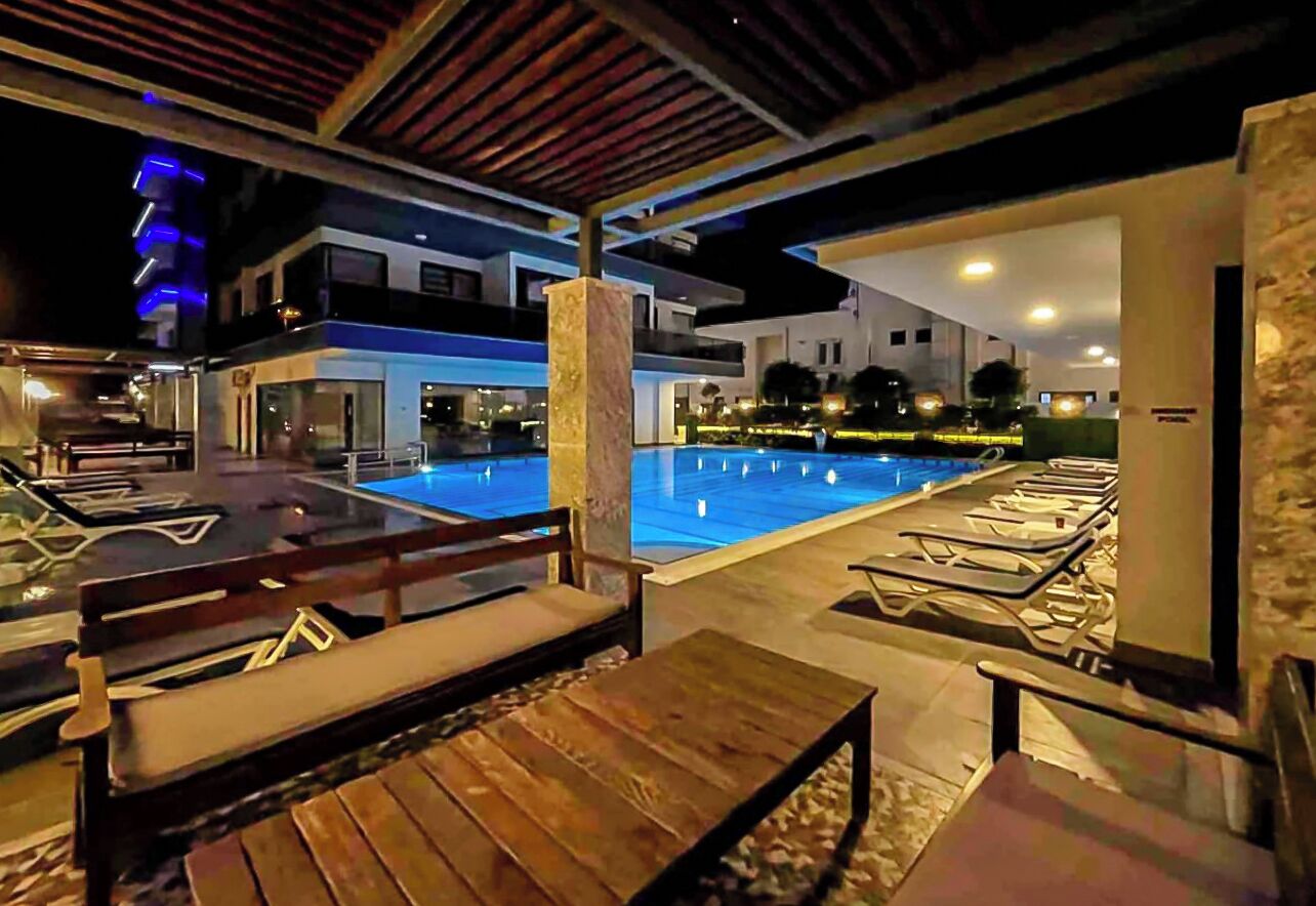 Un espace aménagé au bord de la piscine, avec des chaises longues et une terrasse en bois.