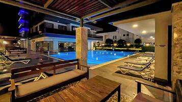 Un espace aménagé au bord de la piscine, avec des chaises longues et une terrasse en bois.