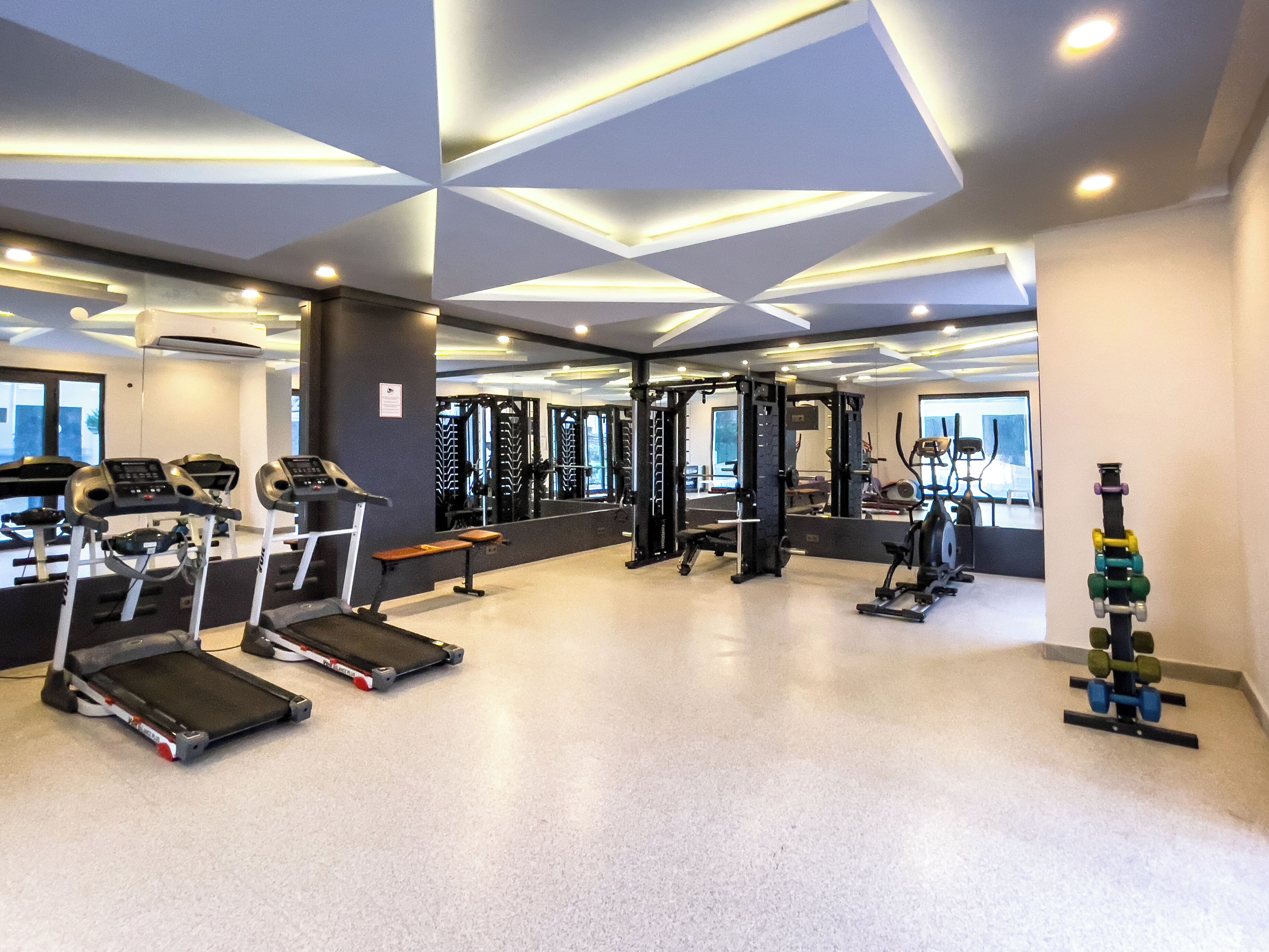 Una palestra moderna con tapis roulant, macchinari per pesi e una parete con specchi.